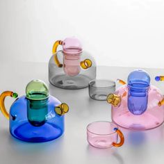 several different colored glass cups sitting next to each other on top of a white table