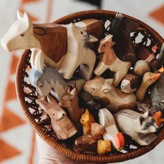 a basket filled with wooden toy animals on top of a table