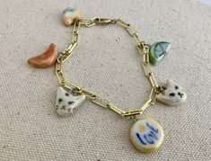 a bracelet with charms on it sitting on top of a carpeted floor next to a wall