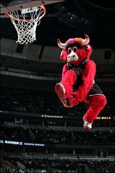 a mascot is in the air above a basketball hoop