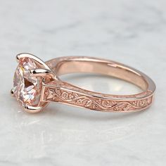 a rose gold engagement ring with an oval cut diamond in the center and filigree band