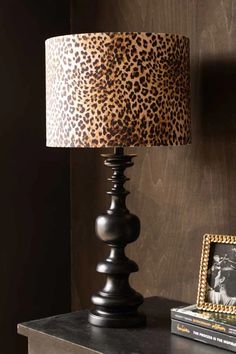 a lamp that is on top of a table next to a book and some pictures