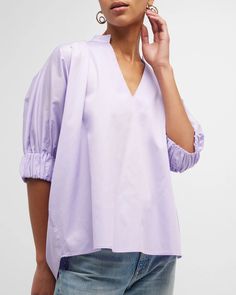 "Medina" Blouse is a this loose-fitting blouse that has become a best-seller. It features a V-neck collar and elbow-length sleeves with elasticized cuffs. Relaxed Fit. Material: 100% Cotton. Model 1 wears size 'S'. Model 2 wears size '1X'. Modern V-neck Blouse For Spring, Spring V-neck Smock Blouse, Spring Smock V-neck Blouse, Spring Blouse With 3/4 Gathered Sleeves, Spring V-neck Top With Pleated Sleeves, Modern Blouse With Balloon Sleeves For Spring, Modern V-neck Blouse For Daywear, Summer V-neck Blouse With Smocked Cuffs, Modern Balloon Sleeve Blouse For Spring