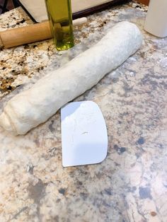 a long piece of bread sitting on top of a counter next to a bottle of olive oil