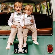 two young boys sitting on the back of a green van wearing bow ties and suspenders