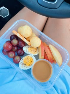 a plastic container filled with assorted fruits and cheese next to a cup of coffee