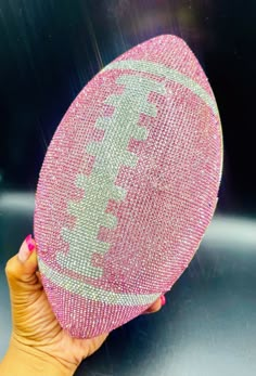 a person holding up a pink and silver object in front of a black background with white letters on it