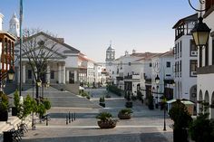 an empty street with white buildings and trees