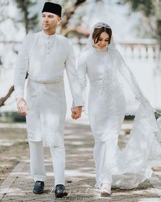 a bride and groom holding hands walking down the street in their traditional wedding attire, dressed in white