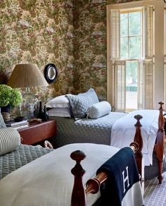 two beds in a bedroom with floral wallpaper