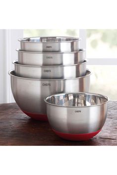 five stainless steel mixing bowls on a wooden table