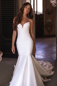 a woman in a white wedding dress posing for the camera with her hand on her hip