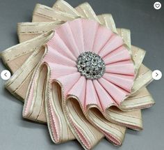 a pink and gold flower brooch sitting on top of a table