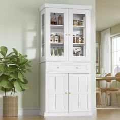 a tall white cabinet sitting next to a potted green plant in a living room