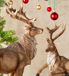 two deer statues standing next to each other in front of a christmas ornament