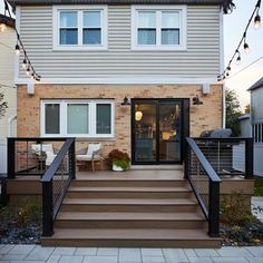 a house with stairs leading up to the front door and patio area, surrounded by string lights