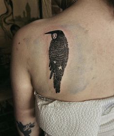 a woman with a black bird tattoo on her back shoulder and arm, which has stars all over it