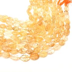 some yellow beads are on a white surface with an orange string in the middle of it