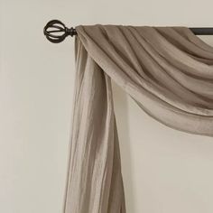 the curtain is pulled back and hung on the wall by a metal rod with an iron hook