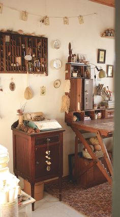 an old fashioned desk and chair in a room with lots of clutter on the wall