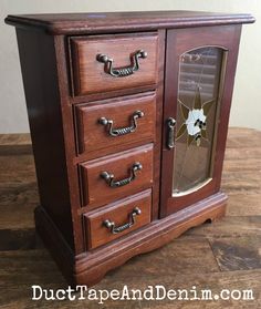 a wooden cabinet with three drawers and one door open on top of it, sitting on a table