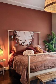 a bed sitting in a bedroom next to a wooden table and plant on top of it