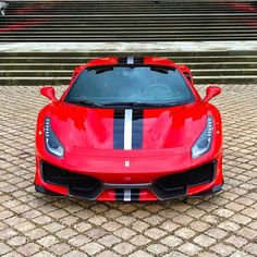 a red sports car parked on top of a brick road next to stairs and steps