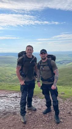 two men with backpacks on top of a hill