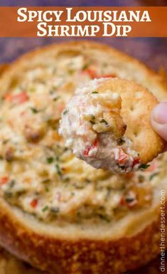 a hand holding a cracker over a bowl of food with the words spicy louisiana shrimp dip on it