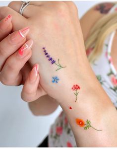 a woman's arm with flowers on it and her hand holding the wrist tattoo