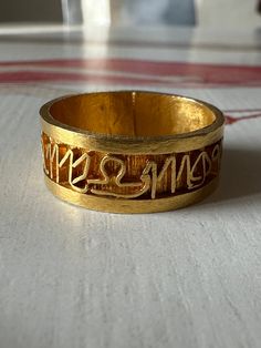 a close up of a gold ring with writing on it