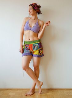 a woman standing in front of a white wall wearing colorful shorts and a bra top