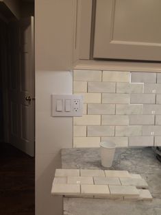 a kitchen with white cabinets and marble counter tops