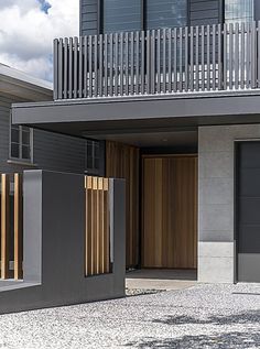 two garage doors are open in front of a modern building with balconies on the second floor