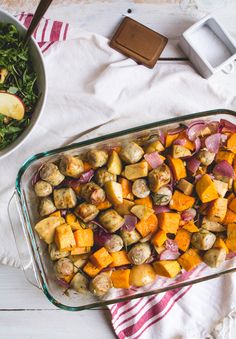 a glass casserole dish filled with vegetables and meats next to a bowl of salad