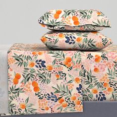 three pillows are stacked on top of each other with oranges and leaves printed on them