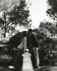 a man and woman are kissing in front of some trees with their arms around each other