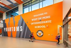 two children are standing in front of an orange wall with the words welcome to west de perre