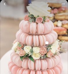 a three tiered pink macaroon cake with flowers on top