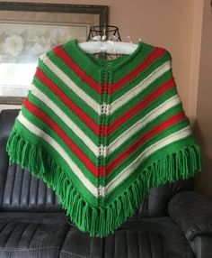 "Beautiful vintage handmade knit poncho in green, red and white. Great to wear in autumn and winter or cold indoor places. I am not sure of the type of yarn. Add a touch of elegance to your outfit with this warm accessory. Measures appropriately:  -wingspan 28\" tip to tip -fringe length 4\" -overall length 21\" from neck to bottom of fringe This stunning poncho is in very good condition. Please see photos. 2023-10" Green One-size Winter Poncho, Green One Size Winter Poncho, Green Shawl Poncho One Size, Green One-size Shawl Poncho, Cozy One-size Green Poncho, Hand Knitted White Poncho For Winter, Cape Wrap, Kids Poncho, Knit Poncho