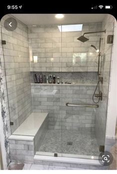 a walk in shower sitting next to a white tiled wall and floor with glass doors