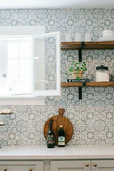 a kitchen with white cabinets and blue wallpaper