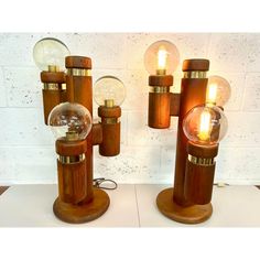 two wooden table lamps with glass globes on them and one light bulb is turned on