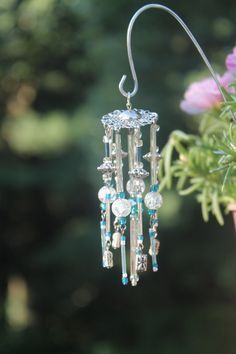 a pair of earrings hanging from a plant with flowers in the backgroung