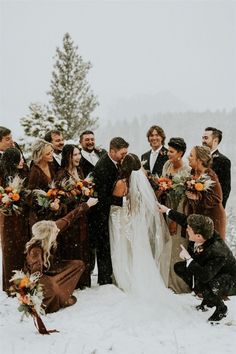 a group of people standing around each other in the snow with flowers on their heads