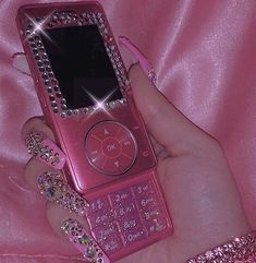 a person holding a pink cell phone with lots of bling on it's screen