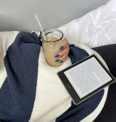 a woman laying on her stomach with a cup of coffee and an ipad