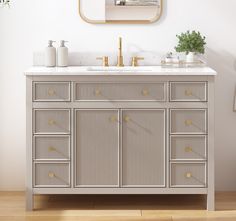 a bathroom vanity with two sinks and a mirror on the wall above it that has gold accents