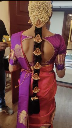 the back of a woman's head with braids in her hair and wearing a purple saree