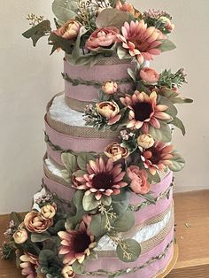 a multi layer cake decorated with flowers and ribbons